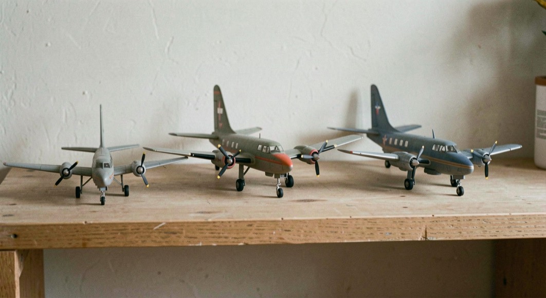 Three finished models of the same propeller aircraft at different scales lined smallest to largest on a plain shelf